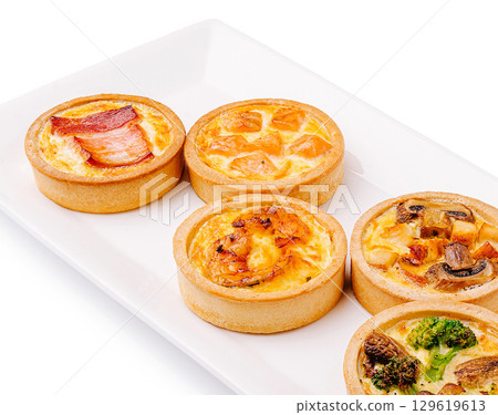 Assorted savory tarts with fillings served on a white platter Assorted savory tarts with fillings served on a white platter 129619613
