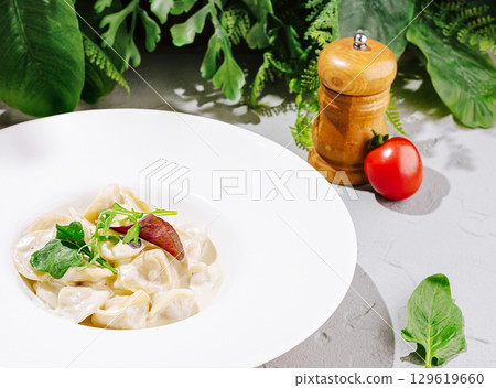 Creamy pasta with fresh herbs and veggies in a bright setting Creamy pasta with fresh herbs and veggies in a bright setting 129619660