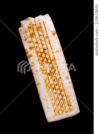 Delicious grilled flatbread with char marks displayed on a black background 129619684