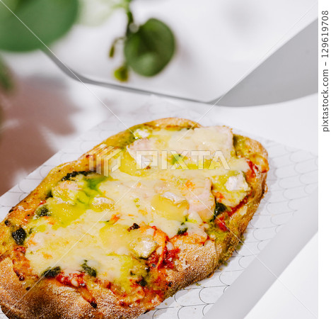 Delicious cheesy flatbread with pesto and tomatoes enjoyed at a casual eatery 129619708