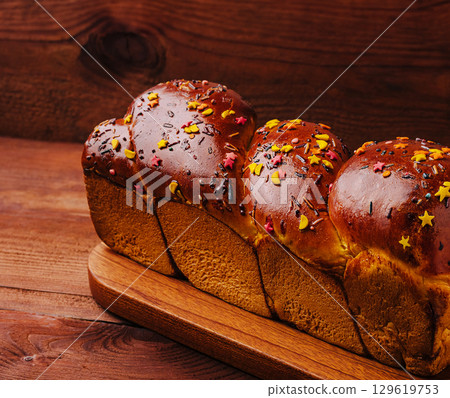 Sweet bread with colorful sprinkles on a wooden board Sweet bread with colorful sprinkles on a wooden board 129619753