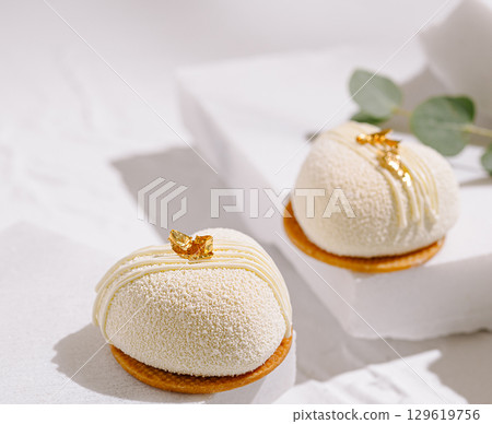 Delicate white desserts on display with gold accents in a serene setting Delicate white desserts on display with gold accents in a serene setting 129619756