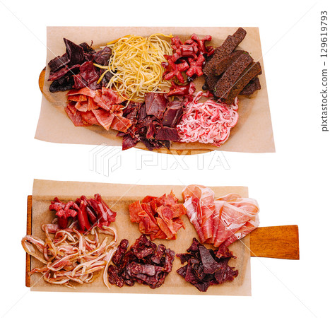 Assorted dried meats and jerky displayed on wooden platters 129619793