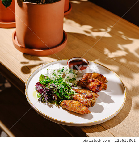 Delicious chicken wings served with fresh salad and dipping sauce 129619801
