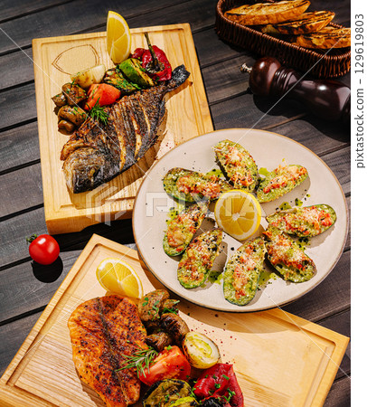 Grilled seafood and vegetables served in elegant wooden platters Grilled seafood and vegetables served in elegant wooden platters 129619803