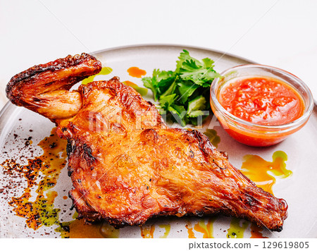 Grilled chicken leg served with salsa and fresh herbs on a plate 129619805