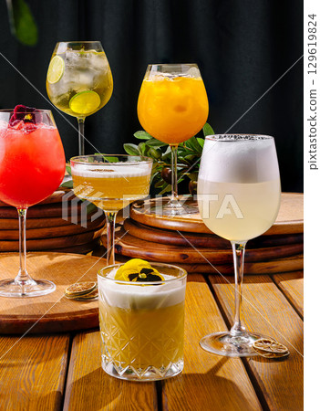 Colorful cocktails displayed on a wooden table at a vibrant bar setting 129619824