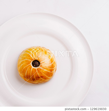 Delicate pastry showcased on a white plate with a minimalistic design Delicate pastry showcased on a white plate with a minimalistic design 129619830