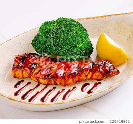 Grilled salmon with broccoli and lemon served on a white plate 129619831