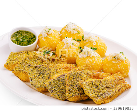 Delicious fried fish served with yellow plantain balls and dipping sauce Delicious fried fish served with yellow plantain balls and dipping sauce 129619833