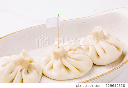 Dumplings served on a simple plate with a small flag for identification 129619838
