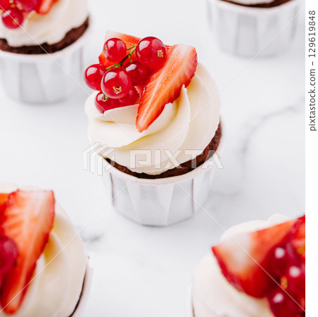 Delightful cupcakes topped with fresh strawberries and currants for dessert Delightful cupcakes topped with fresh strawberries and currants for dessert 129619848