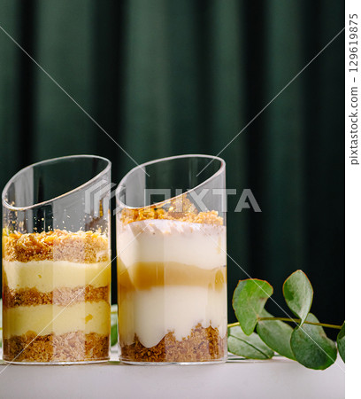 Desserts in elegant glass cups with layers of cream and crumbs 129619875