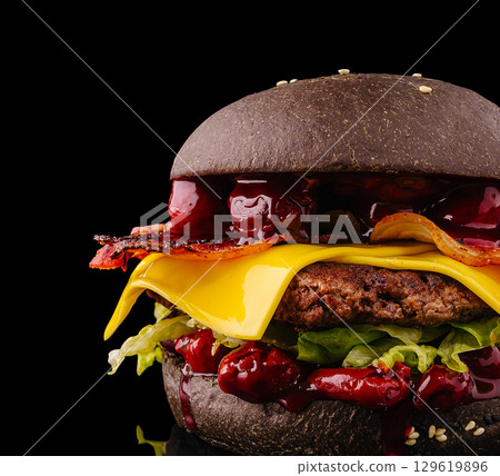 Black burger with multiple toppings served on a reflective surface Black burger with multiple toppings served on a reflective surface 129619896