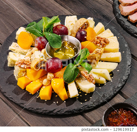 Cheese and fruit platter with honey served on a slate board at a gathering Cheese and fruit platter with honey served on a slate board at a gathering 129619917