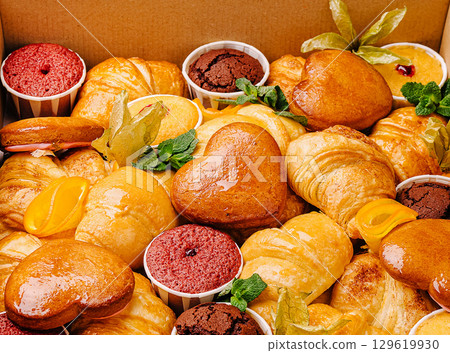 Delicious assortment of pastries and desserts in a bakery box in daylight Delicious assortment of pastries and desserts in a bakery box in daylight 129619930