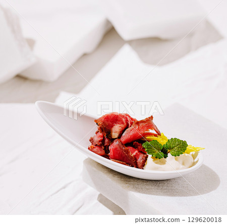 Artfully presented gourmet dish with meat and sauce on a white background Artfully presented gourmet dish with meat and sauce on a white background 129620018