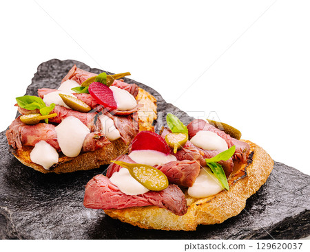 Delicious roast beef tartines served on dark stone plate at lunchtime Delicious roast beef tartines served on dark stone plate at lunchtime 129620037