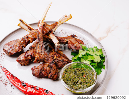 Grilled lamb chops served with spicy green sauce and herbs 129620092