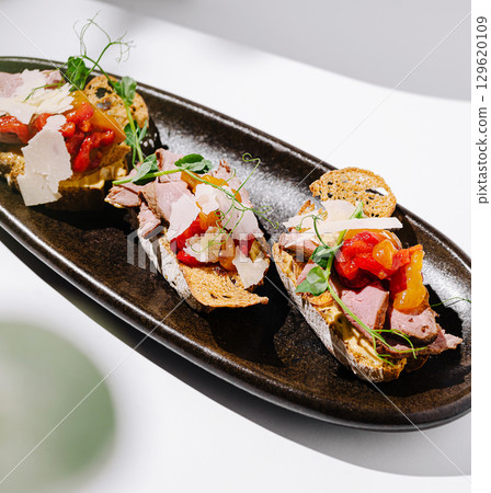 Delicious open-faced sandwiches served on a sleek black platter Delicious open-faced sandwiches served on a sleek black platter 129620109