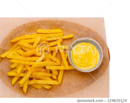 Crispy fries served with creamy dipping sauce on a wooden platter 129620124