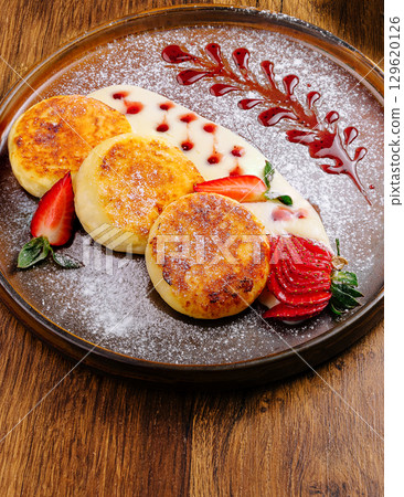 Delicious cottage cheese pancakes with cream, berries, and powdered sugar 129620126
