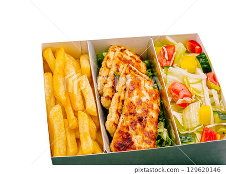 Delicious grilled chicken with fries and fresh salad served in a takeaway box 129620146