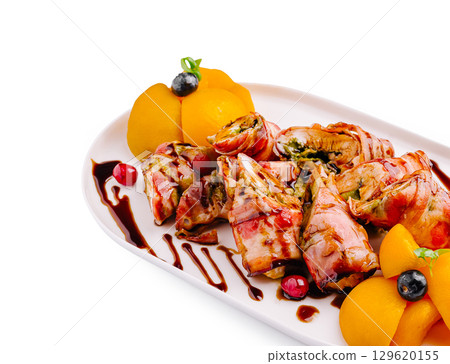 Delicious gourmet dish with bacon-wrapped vegetables and fruits served elegantly 129620155