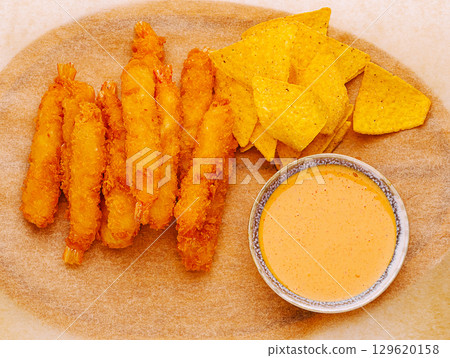 Shrimp fritters served with chips and dipping sauce on a wooden tray 129620158