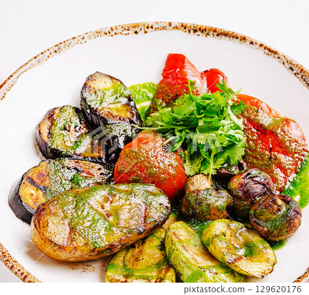 Grilled vegetables with fresh herbs on a rustic plate at a summer gathering 129620176