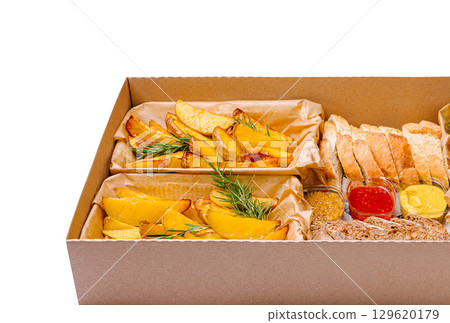 Delicious baked potato wedges served with dips and bread in a takeout box 129620179