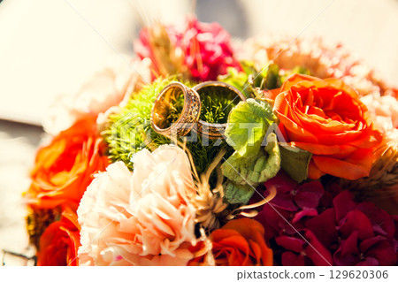 Wedding rings on the bride's bouquet in the autumn theme 129620306