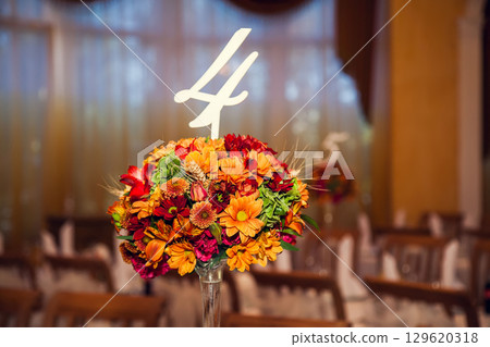 The hall in the restaurant, decorated with flowers in the autumn style. Wedding decor in autumn flowers and floral arrangements The hall in the restaurant, decorated with flowers in the autumn style. Wedding decor in autumn flowers and floral arrangements 129620318