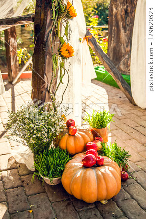 Wedding arch for off-site wedding ceremony, decorated in autumn theme with pumpkins 129620323