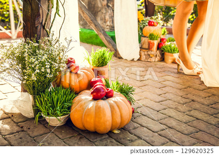 Wedding arch for off-site wedding ceremony, decorated in autumn theme with pumpkins 129620325
