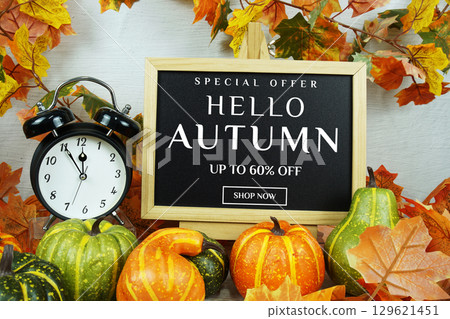 Autumn Sale 60% text with alarm clock and maple leaf decoration on wooden background Autumn Sale 60% text with alarm clock and maple leaf decoration on wooden background 129621451