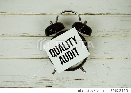 Quality Audit text message on paper with alarm clock on wooden background Quality Audit text message on paper with alarm clock on wooden background 129622113