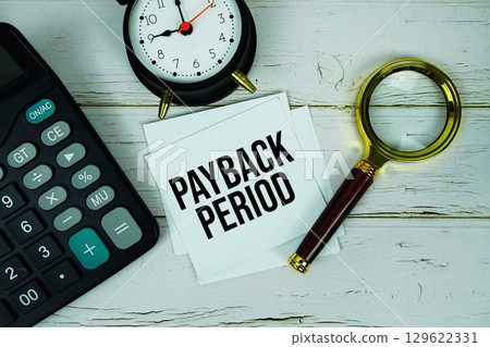 Payback Period text message on paper with magnifying glass, calculator and alarm clock on wooden background Payback Period text message on paper with magnifying glass, calculator and alarm clock on wooden background 129622331