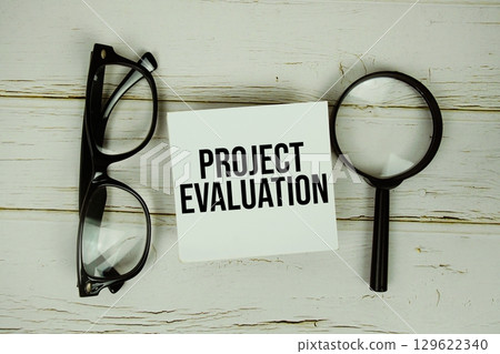 Project Evaluation text message on paper with magnifying glass and eyeglasses on wooden background 129622340