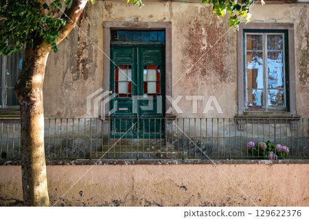 Old house facade with weathered walls, green door, and windows Old house facade with weathered walls, green door, and windows 129622376