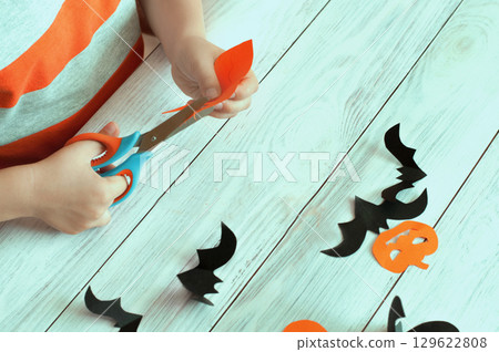 Helowein concept, children's hands carving pumpkins and bats out of paper  129622808