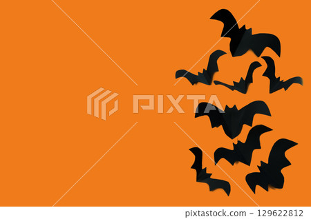 Halloween concept, black paper bats on an orange background Halloween concept, black paper bats on an orange background 129622812