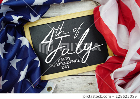 Happy 4th Of July Independence Day text on blackboard with USA flag American holiday background Happy 4th Of July Independence Day text on blackboard with USA flag American holiday background 129623059