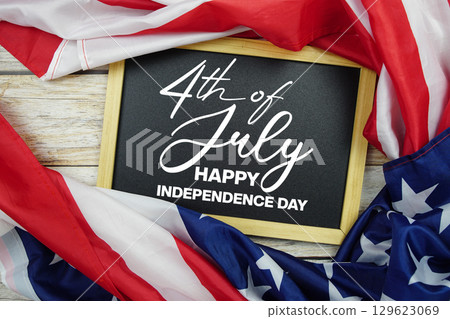 Happy 4th Of July Independence Day text on blackboard with USA flag American holiday background Happy 4th Of July Independence Day text on blackboard with USA flag American holiday background 129623069