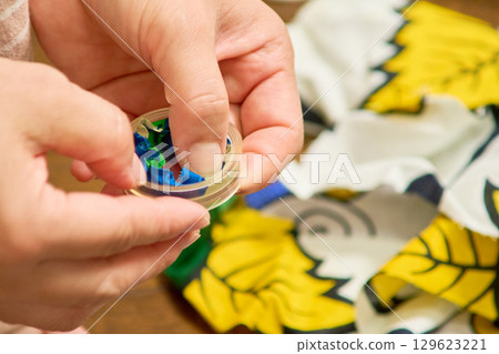 Close-up of a woman's hands making handmade accessories. The process of making a button. Close-up of a woman's hands making handmade accessories. The process of making a button. 129623221