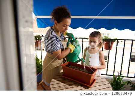 Mother and Daughter Gardening Together on a Balcony 129623479