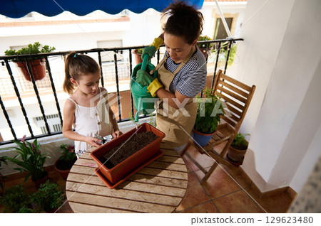 Mother and Daughter Gardening Together on Home Balcony Mother and Daughter Gardening Together on Home Balcony 129623480