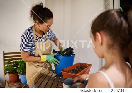 Mother and Daughter Gardening Together on a Sunny Balcony Mother and Daughter Gardening Together on a Sunny Balcony 129623493