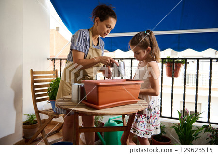 Mother and Daughter Gardening Together on a Balcony Urban Setting 129623515