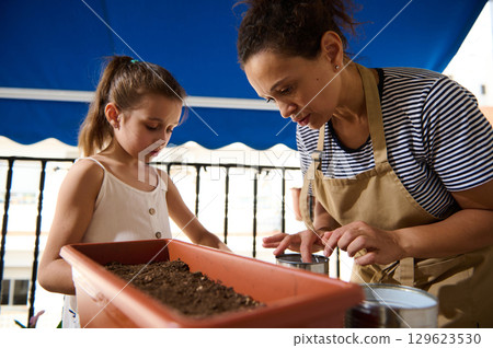 Mother and Child Enjoy Gardening Together on a Sunlit Balcony Mother and Child Enjoy Gardening Together on a Sunlit Balcony 129623530